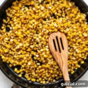 Sunshine Corn Salsa 8 Corn searing in a skillet with a wooden spoon.