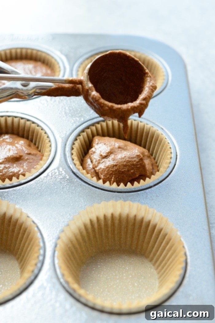 Guilt-Free Chocolate Pumpkin Muffins 4 Rich chocolate pumpkin muffin batter being carefully scooped into a prepared muffin tin, indicating the next step in baking these delicious treats.
