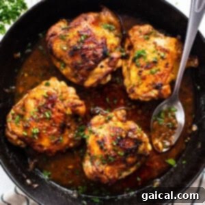 Chicken thighs in a skillet with sauce and herbs.