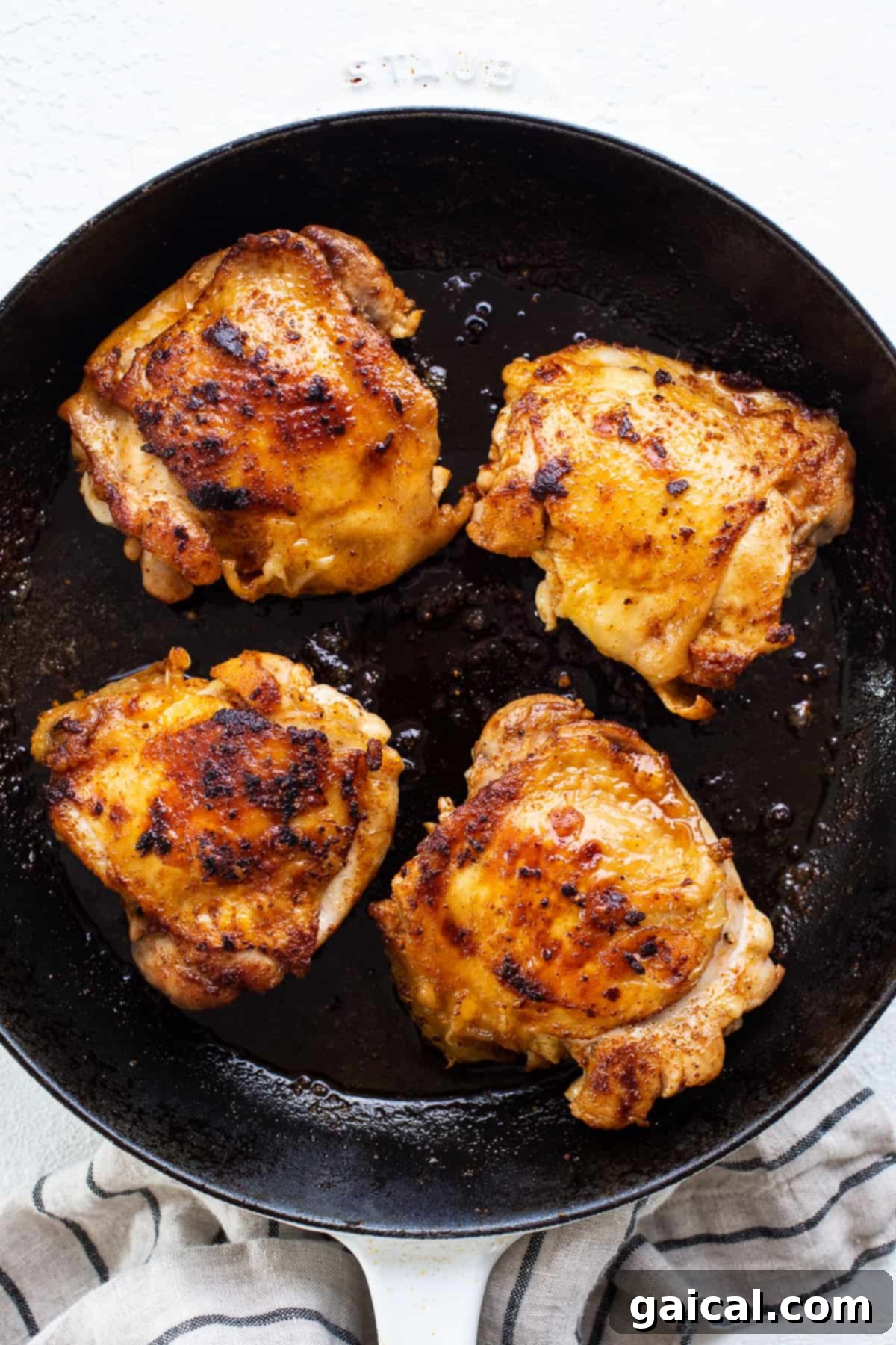 Crispy chicken thighs searing in a cast iron skillet