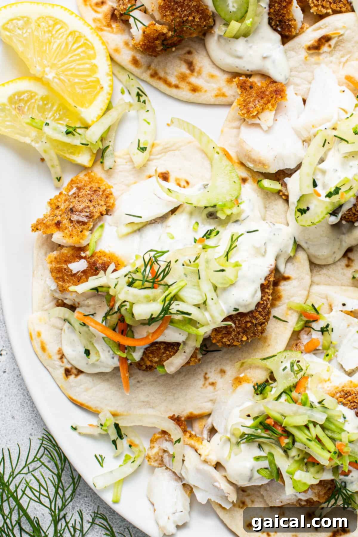 Crispy Air Fryer Fish Tacos 2 Fish tacos with slaw and lemon wedges on a plate.