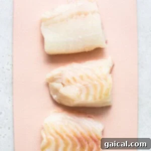Raw cod on a cutting board.