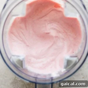 Protein-Packed Strawberry Shortcake Ice Cream Bars 10 Smooth, pink whipped cream being blended in a food processor, indicating a creamy texture.