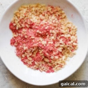 Protein-Packed Strawberry Shortcake Ice Cream Bars 13 Pink granola mixture in a white bowl, ready to be used as a topping.