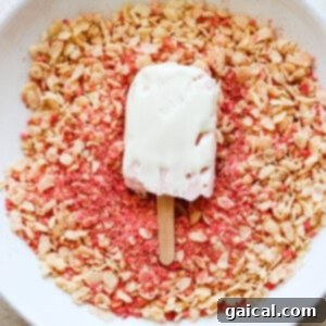 Protein-Packed Strawberry Shortcake Ice Cream Bars 15 A bowl of pink granola with a strawberry popsicle resting on top, ready for final preparation.