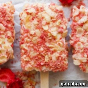 Protein-Packed Strawberry Shortcake Ice Cream Bars 16 Three perfectly coated popsicles, garnished with fresh strawberries and almond slivers, ready to be enjoyed.