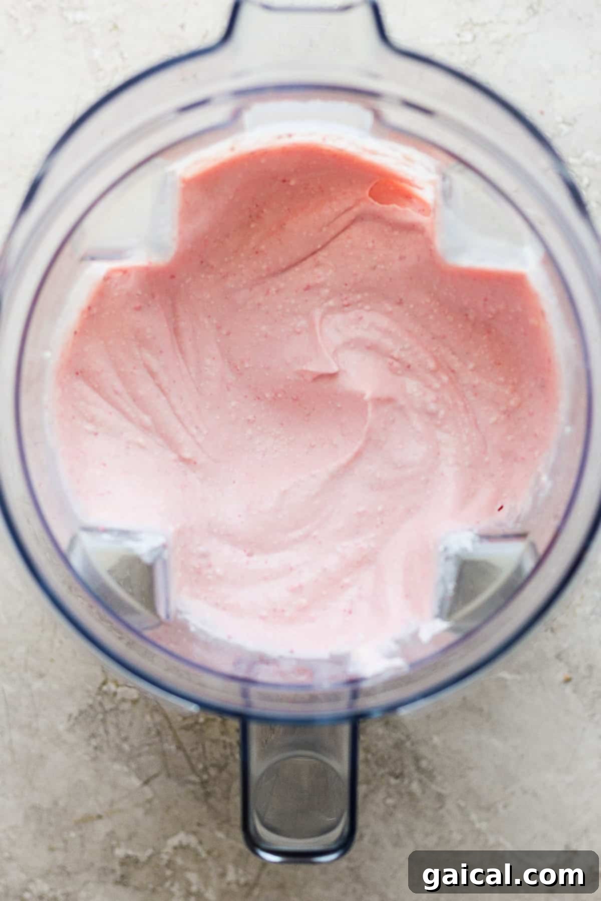 Protein-Packed Strawberry Shortcake Ice Cream Bars 5 Smooth, pink whipped cream being blended in a food processor, indicating a creamy texture.