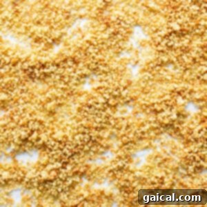 Cooked quinoa spread out evenly on a parchment-lined baking sheet, prepared for the crucial toasting process.