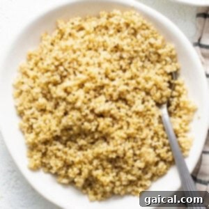A bowl of perfectly cooked, fluffy quinoa with a spoon, highlighting its ideal texture for various recipes.