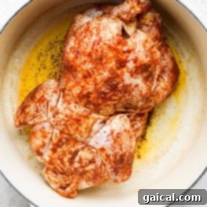 One-Pot Spanish Roast Chicken Dinner 10 A whole chicken browning in a skillet on a white background.