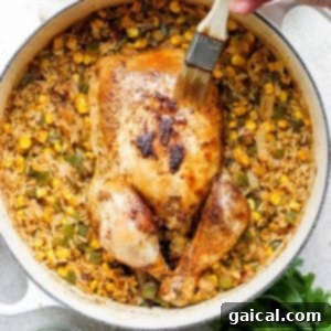 One-Pot Spanish Roast Chicken Dinner 14 A person is slicing a whole chicken and rice in a skillet.