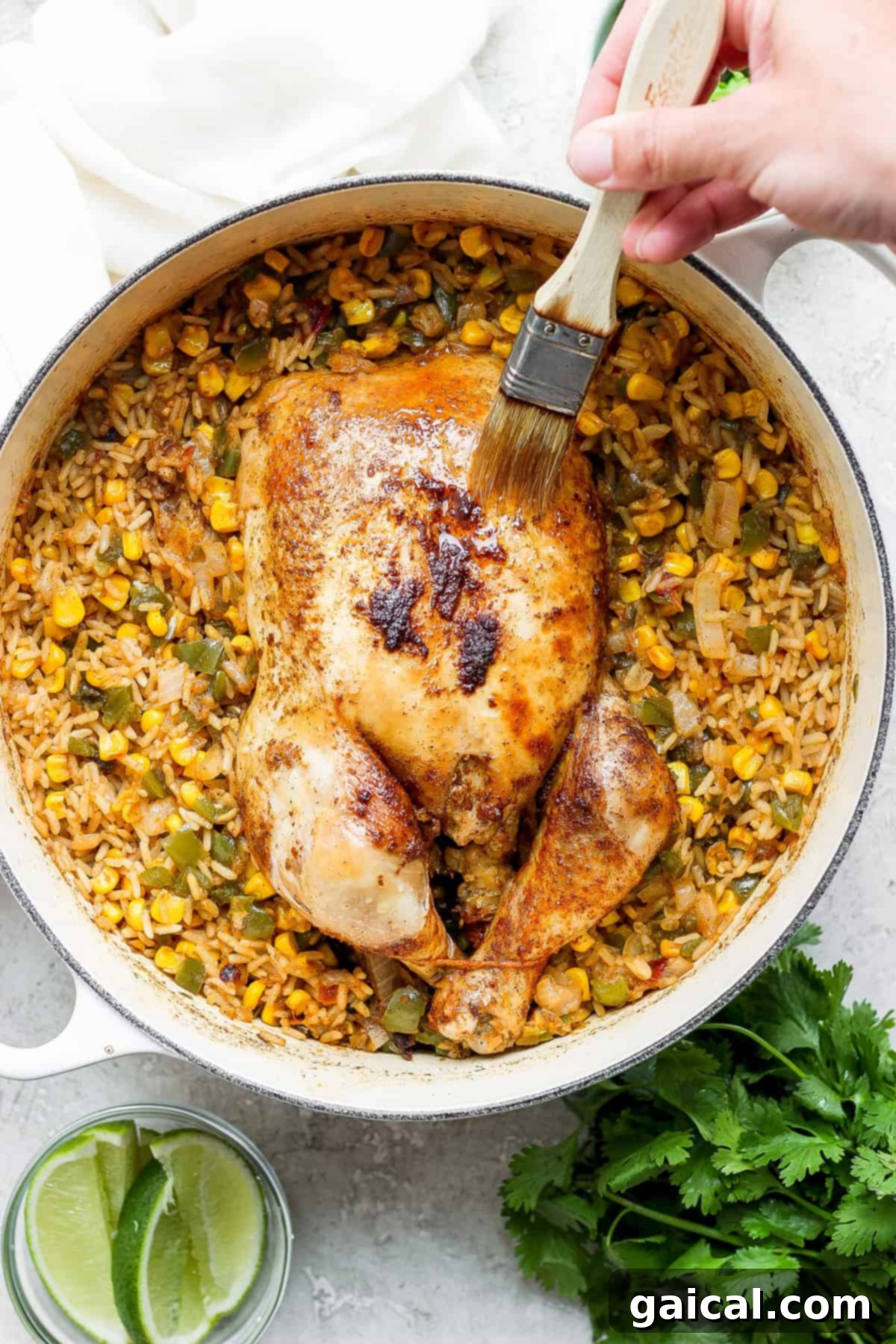 One-Pot Spanish Roast Chicken Dinner 7 A person is slicing juicy roasted chicken over a bed of Spanish rice in a skillet.