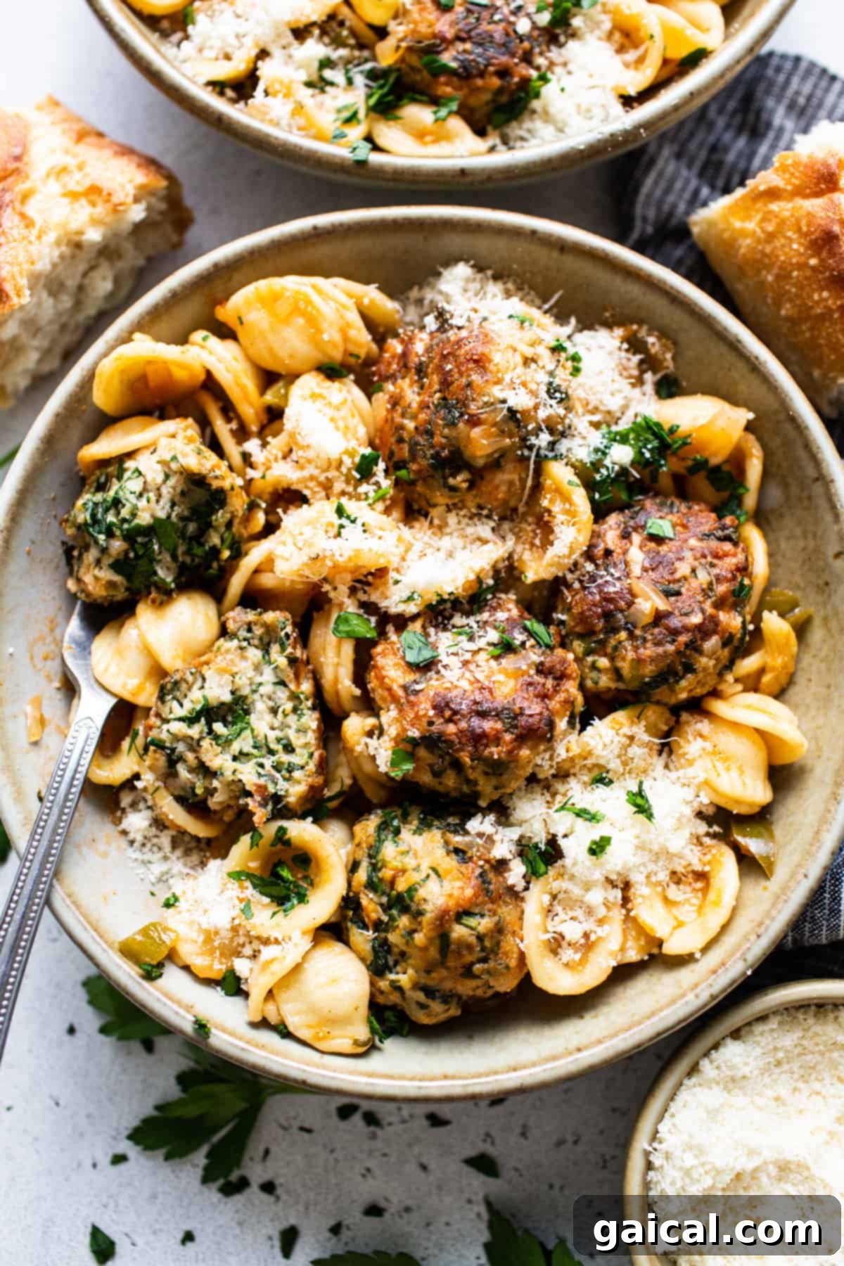 A bowl of pasta with Tuscan chicken meatballs and freshly grated parmesan.