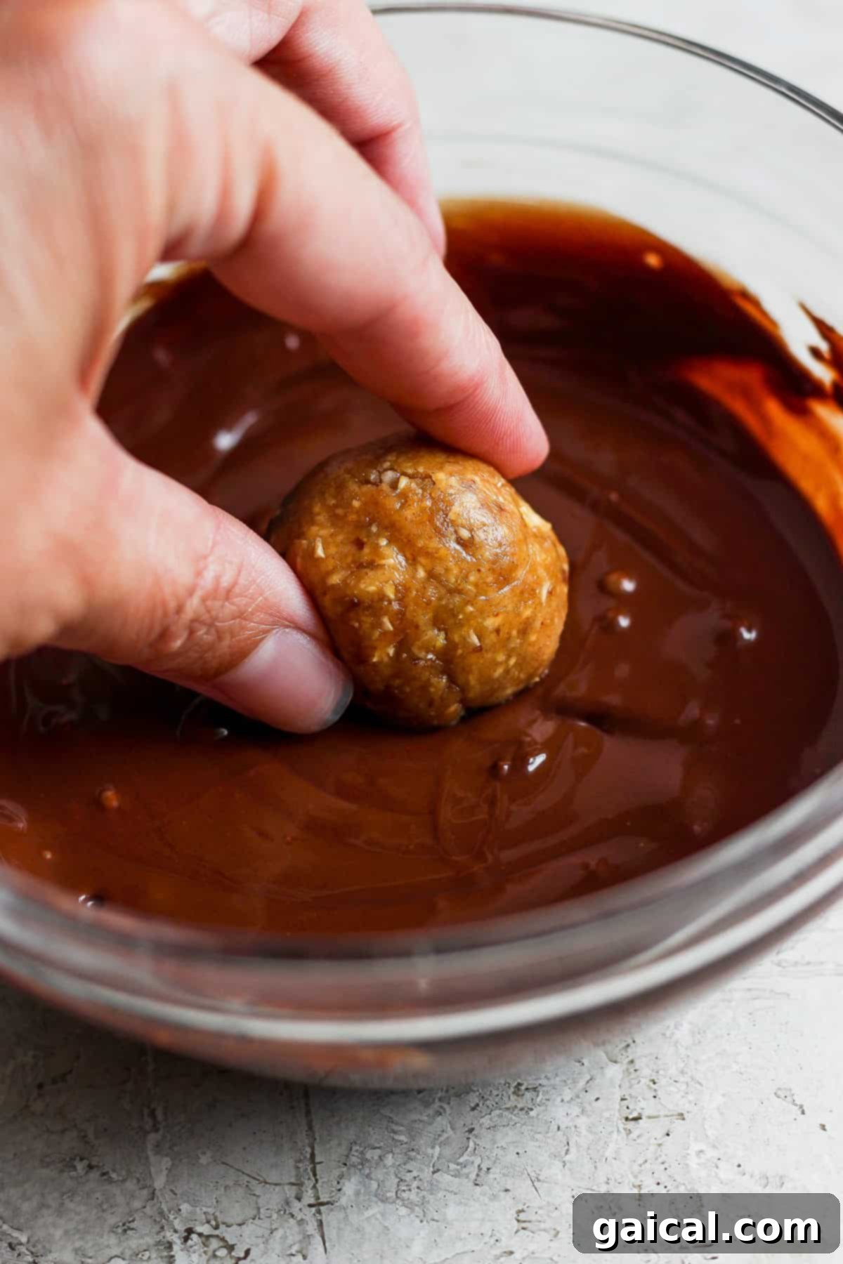 Autumn's Wholesome Kitchen Collective 7 A person dipping a healthy snack into chocolate sauce, symbolizing the delicious indulgence of homemade treats.