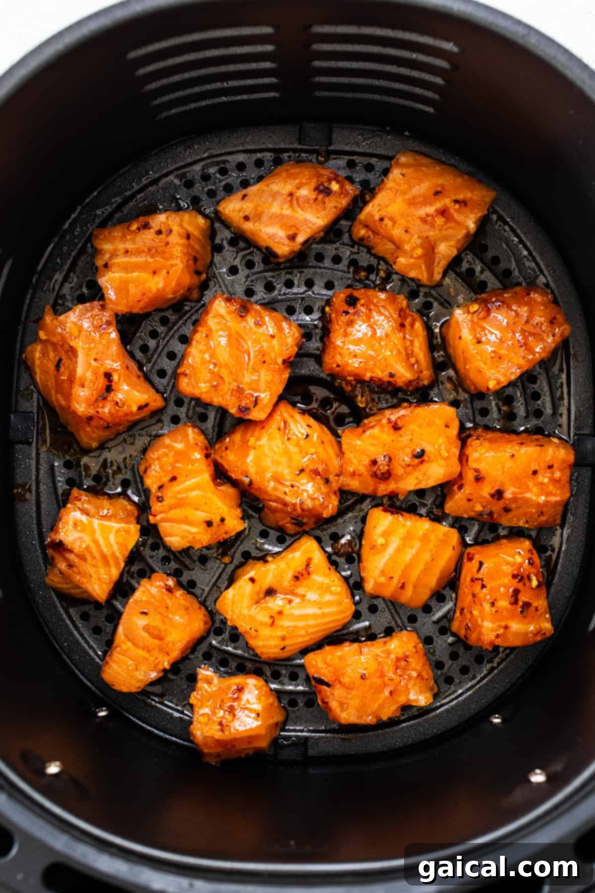 Golden Honey Chili Air Fryer Salmon Bites 5 A close-up view of the honey chili crunch salmon bites cooking to perfection in an air fryer basket, showcasing their developing golden-brown and crispy exterior.
