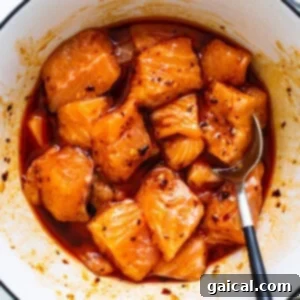 Golden Honey Chili Air Fryer Salmon Bites 8 Salmon cubes being tossed in the honey chili crunch marinade, ensuring every piece is coated before cooking.