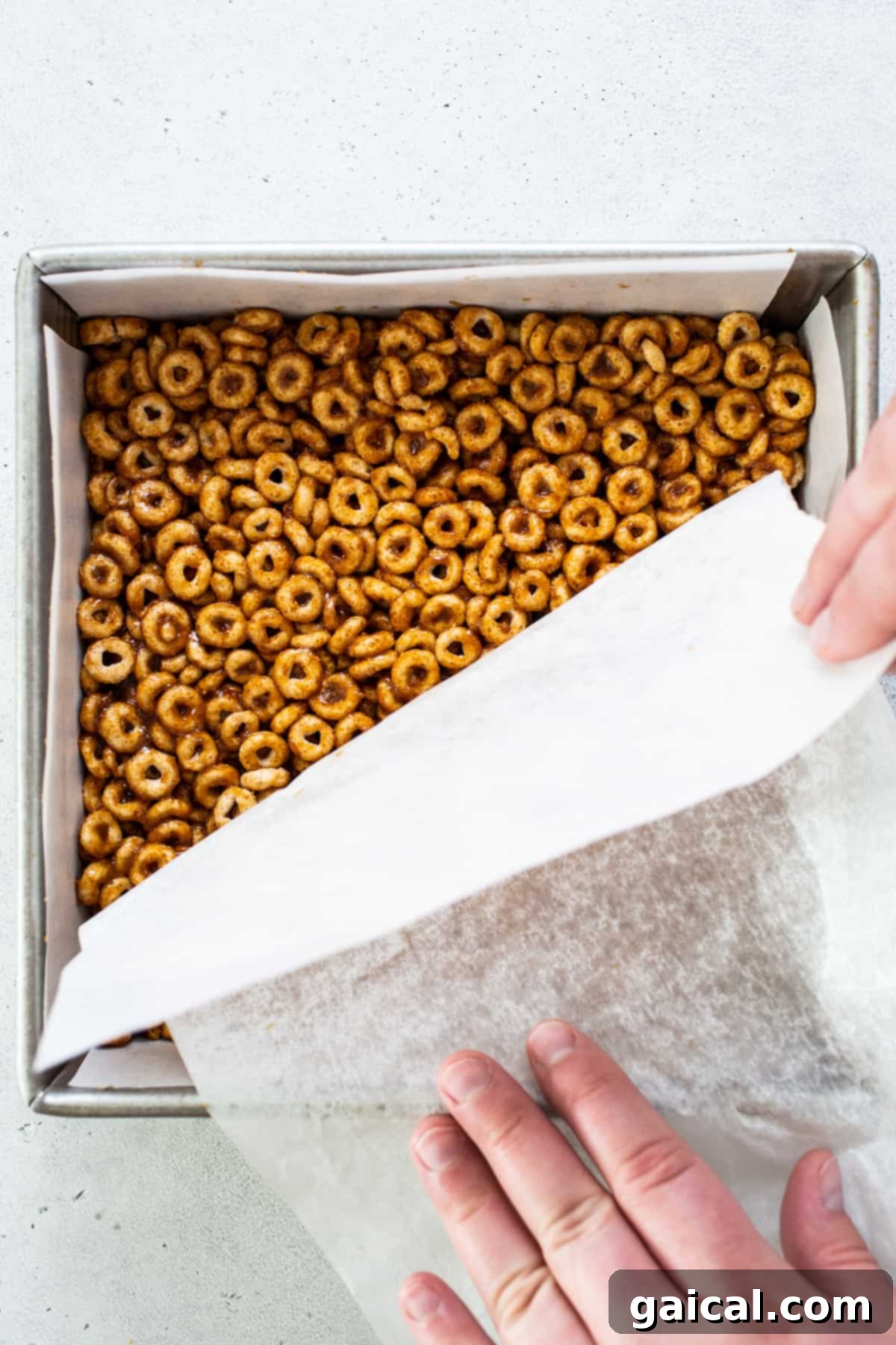 Pumpkin PB Cereal Bars 5 A person putting pretzels in a baking pan.