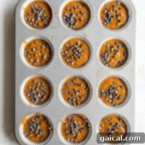 Cozy Pumpkin Spice Muffins 7 Pumpkin chocolate chip muffin batter carefully scooped into a muffin tin, filling each cup to the perfect level before baking.