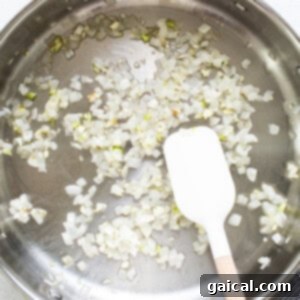 Sauteing diced white onions in a large skillet with avocado oil using a wooden spatula until softened.