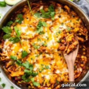 Delicious one-pot chicken enchilada skillet ready to serve, with a wooden spoon.
