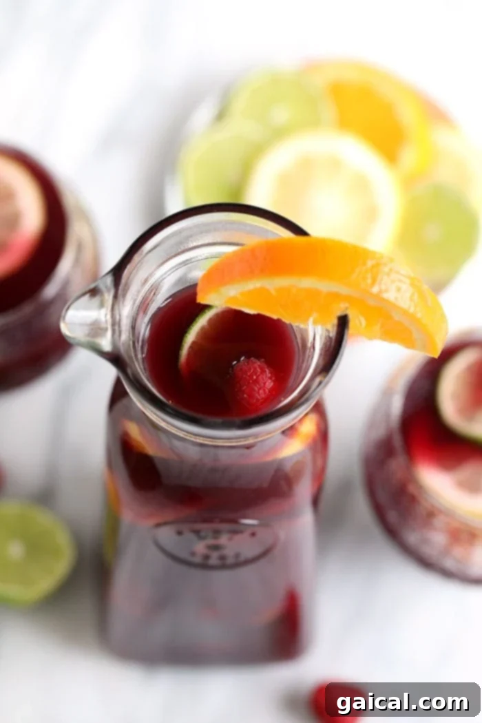 Delicious Homemade Red Wine Sangria with Citrus Easy red wine sangria with vibrant orange slices and raspberries in a glass pitcher, garnished with fresh mint.