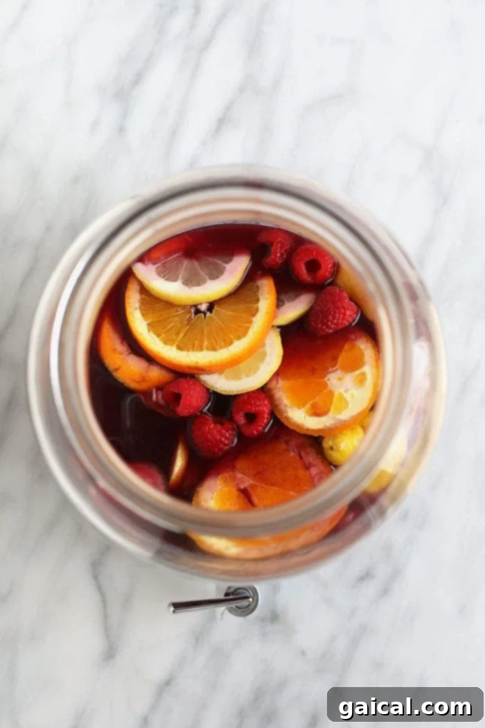 Simple Homemade Sangria Recipe A glass pitcher filled with homemade sangria, garnished with fresh fruit slices, ready to be served.