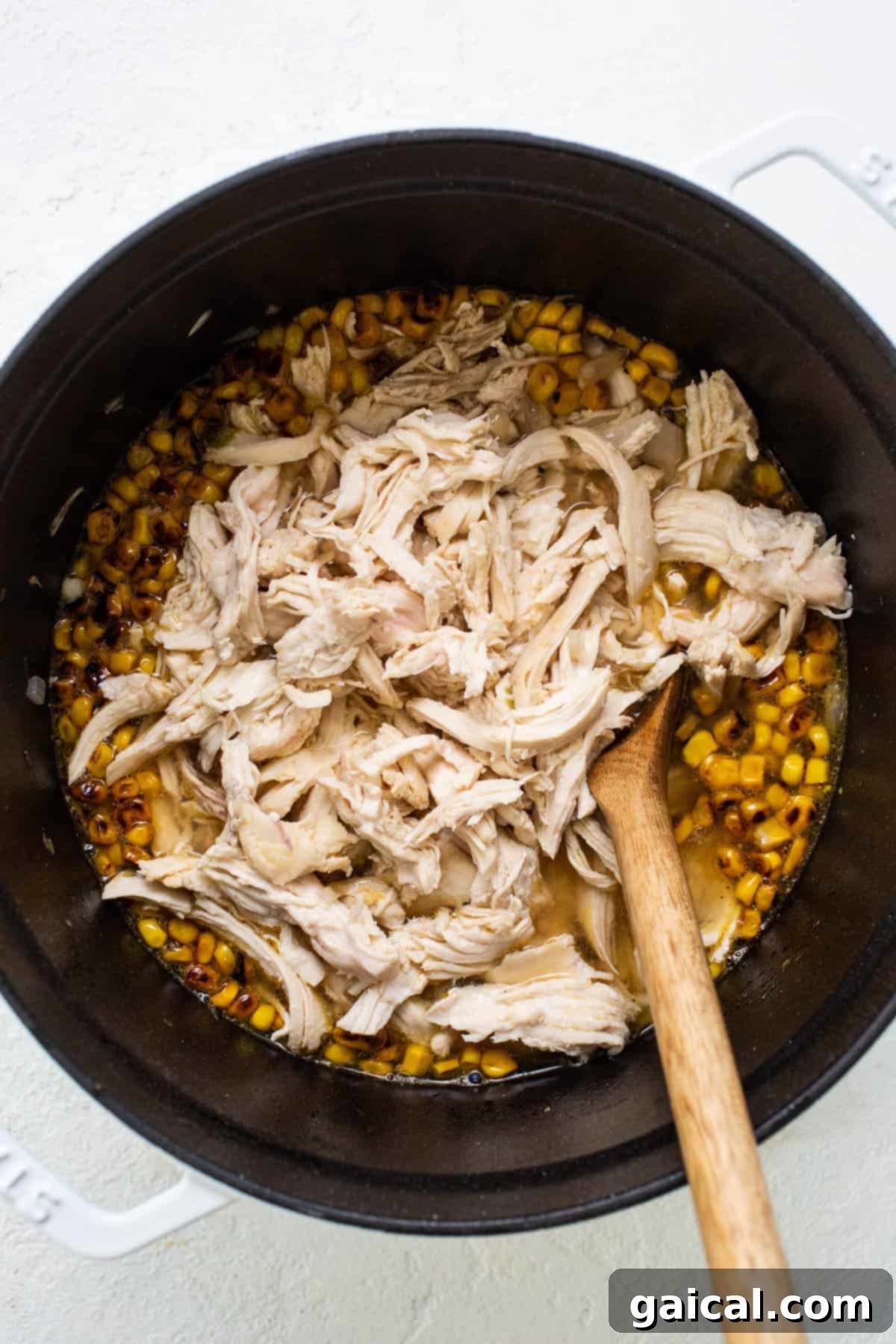 Close-up shot of seasoned chicken and perfectly browned corn simmering in a rich, aromatic broth within a large stockpot. The ingredients meld together, hinting at the flavorful Street Corn Chicken Chili soon to be served.