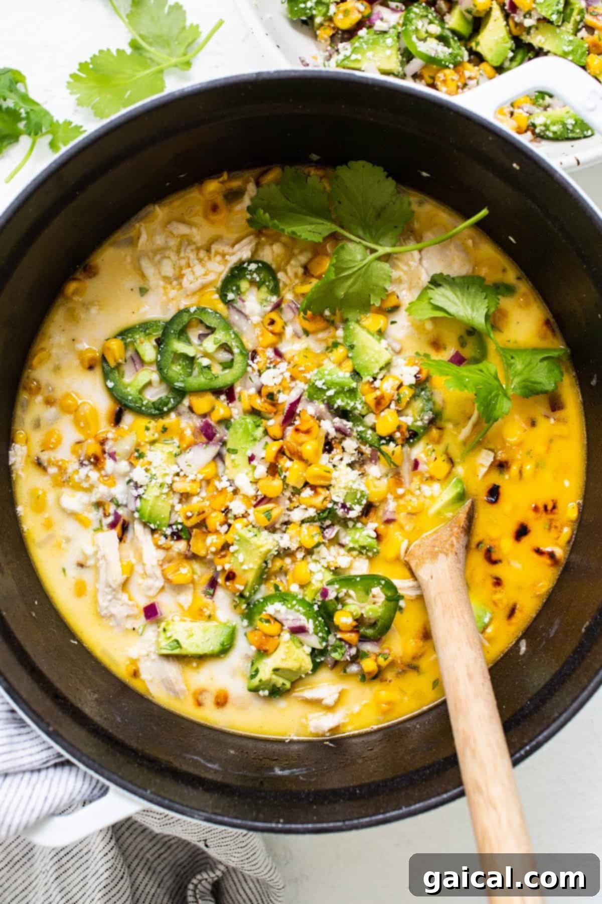 A hearty stockpot brimming with simmering Street Corn Chicken Chili, showcasing its rich, creamy texture and colorful array of ingredients. The chili is nearly ready for its delicious street corn toppings.