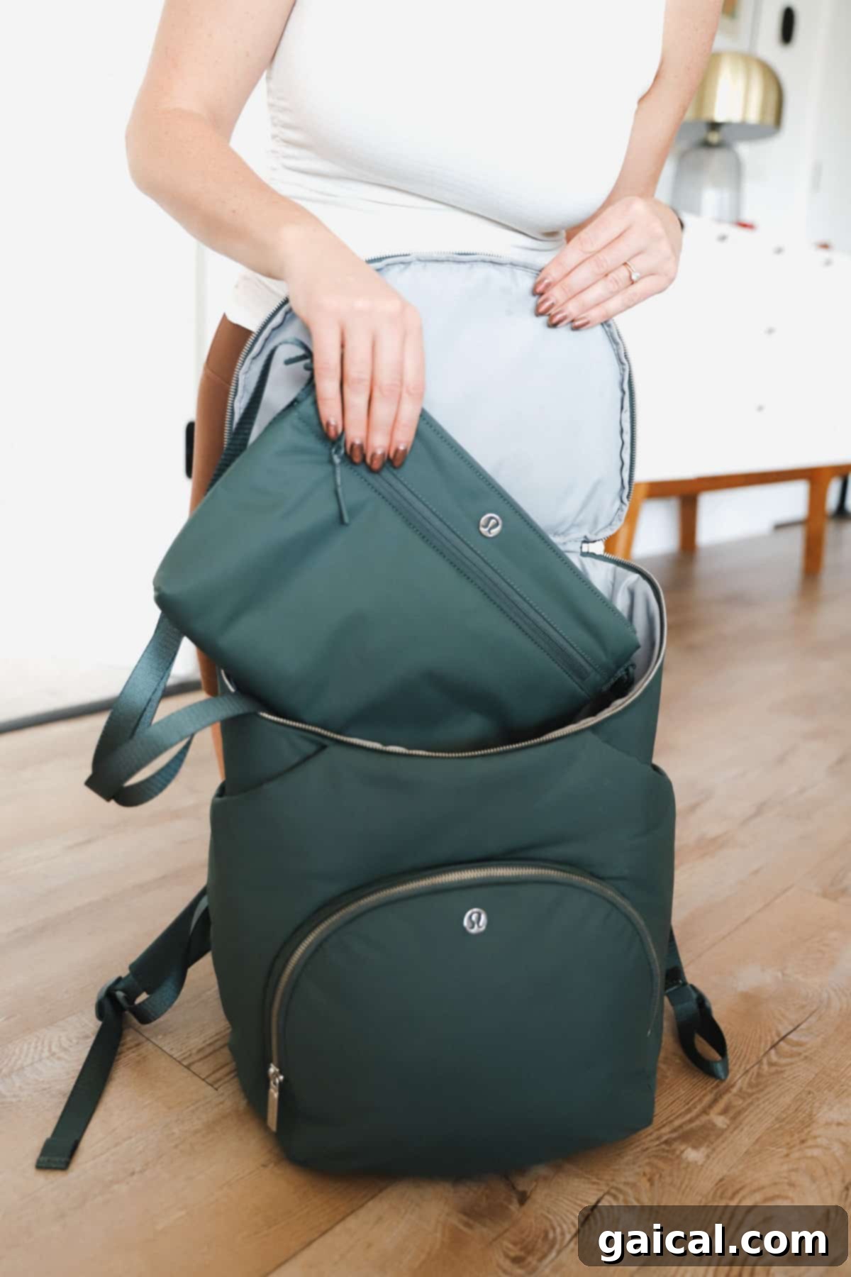 Lululemon Modern Parent Carryall 4 A woman in activewear is holding a stylish emerald green Lululemon New Parent Backpack, showing its dual zippered compartments and sleek silhouette, ready for daily adventures.