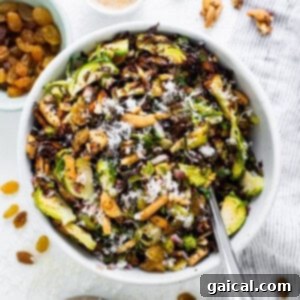 A bowl of brussels sprouts salad with nuts and raisins.