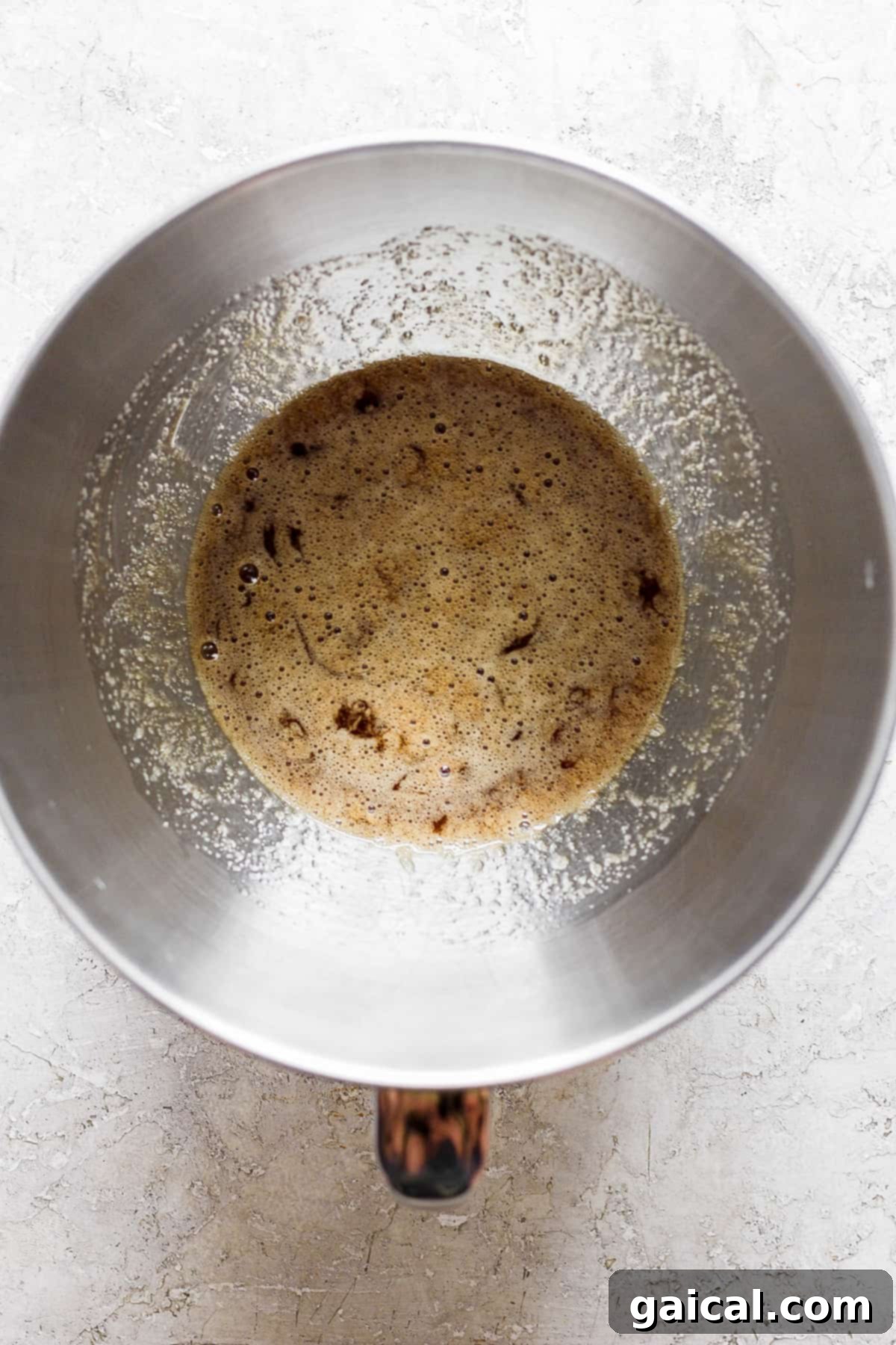 A stainless steel saucepan with simmering water, ready for the double boiler method to heat egg whites and brown sugar.