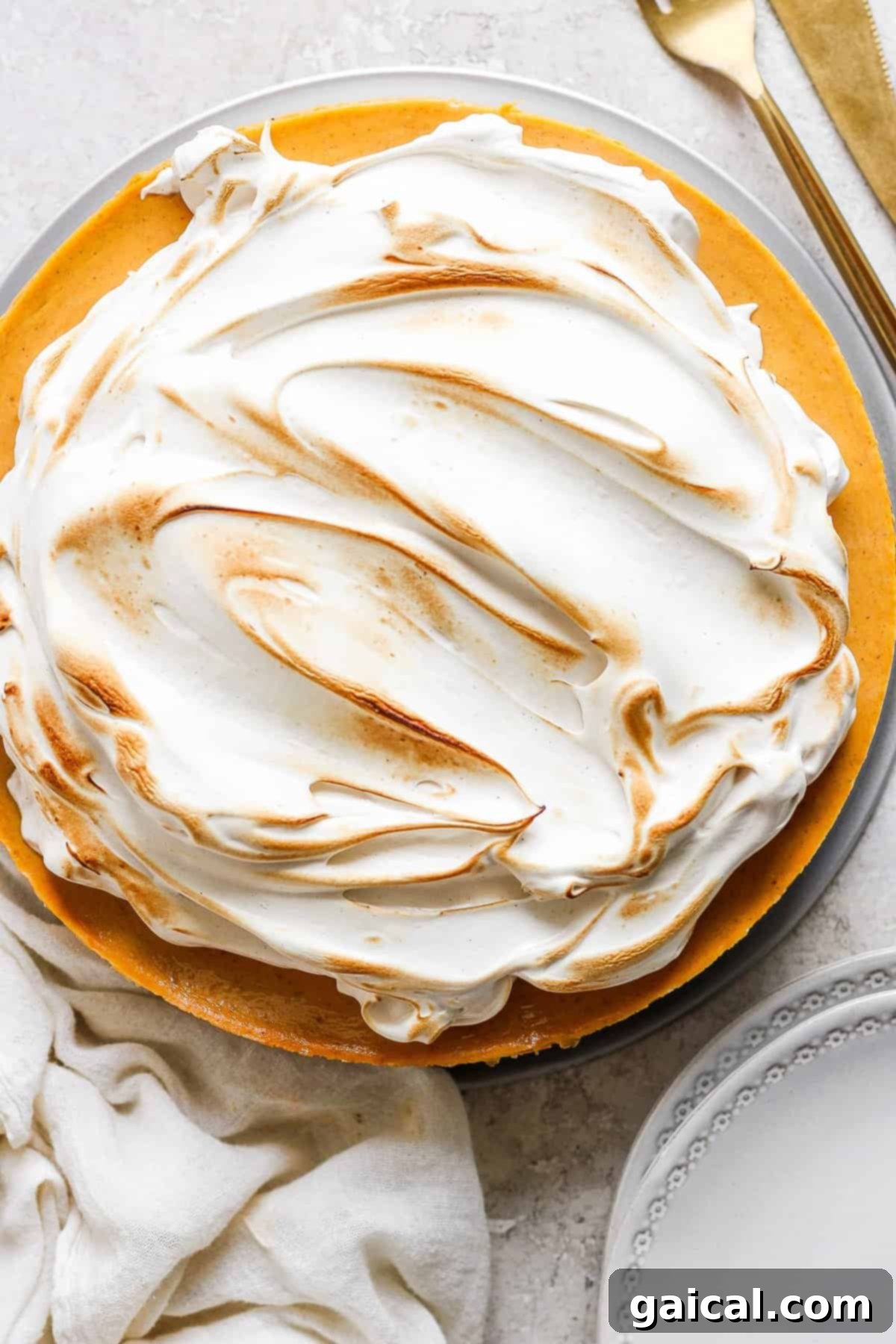 A freshly baked pie adorned with a generous topping of golden brown sugar Swiss meringue, artfully torched.