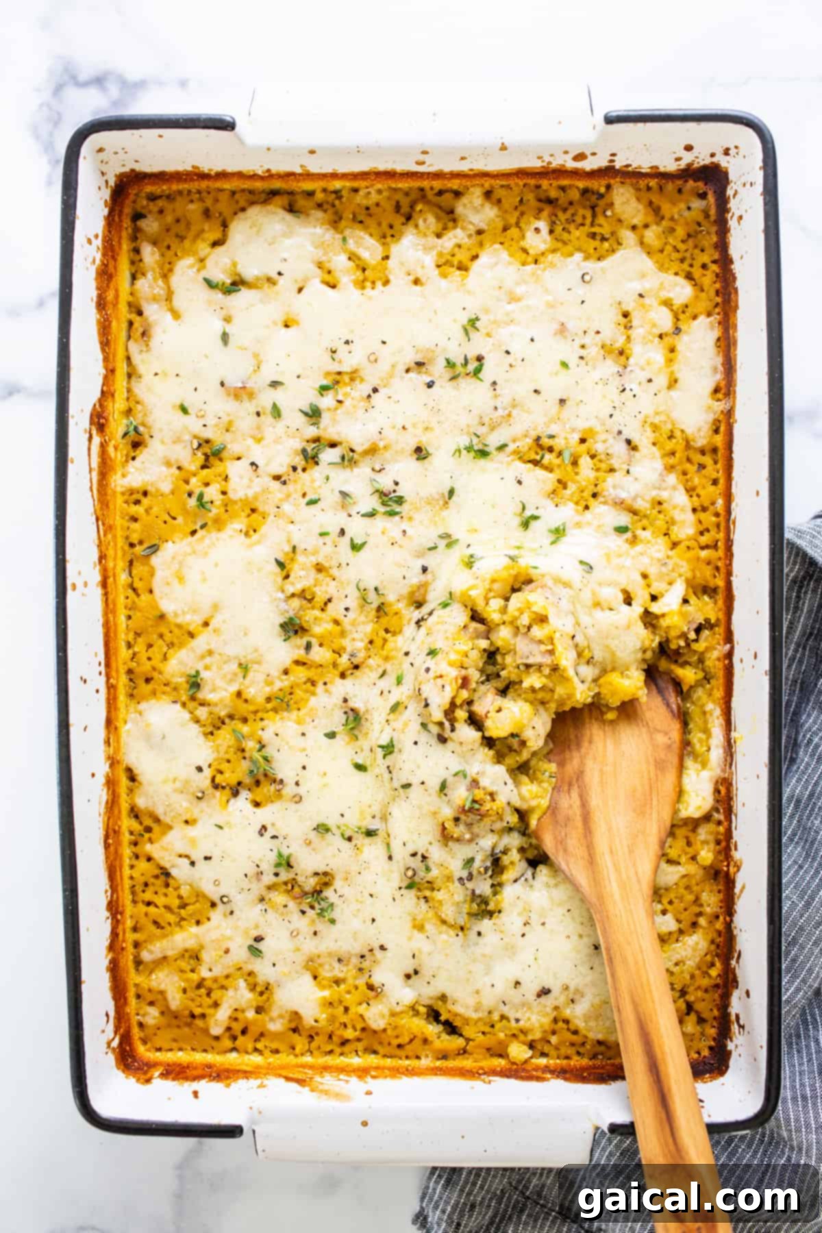 Hearty Butternut Chicken Sausage Quinoa Bake 2 A casserole dish with a wooden spoon in it, showcasing a rich butternut squash and quinoa blend.