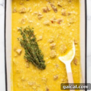 Hearty Butternut Chicken Sausage Quinoa Bake 10 A bowl of soup with a spoon and a sprig of thyme, symbolizing the aromatic addition.