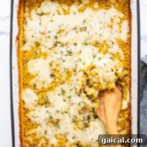 Hearty Butternut Chicken Sausage Quinoa Bake 12 A casserole dish with a wooden spoon in it, showcasing the finished dish.