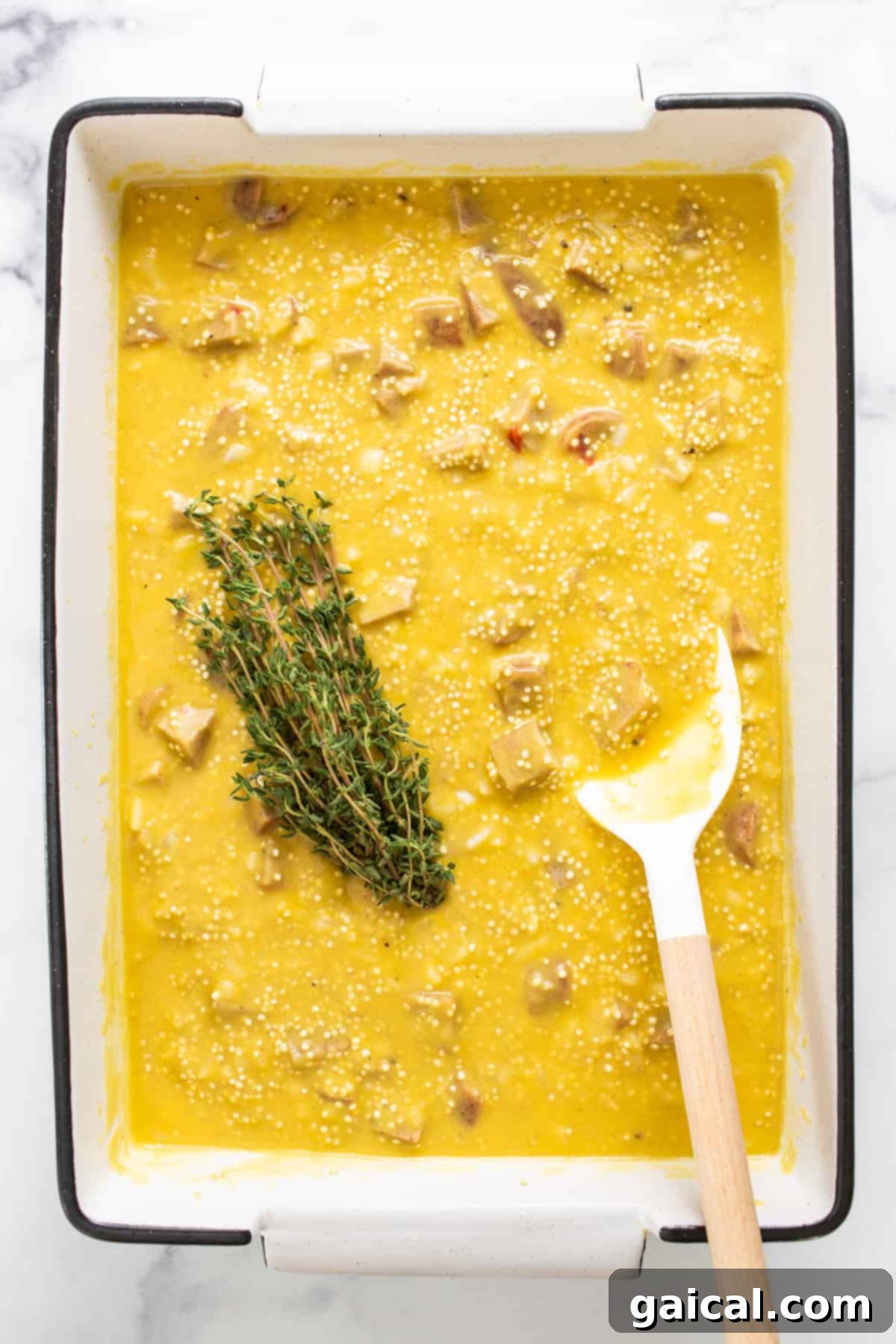 Hearty Butternut Chicken Sausage Quinoa Bake 5 A bowl of creamy soup adorned with a spoon and a sprig of fresh thyme.