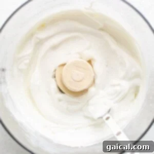 A bowl of creamy whipped cottage cheese in a food processor, highlighting its smooth texture.