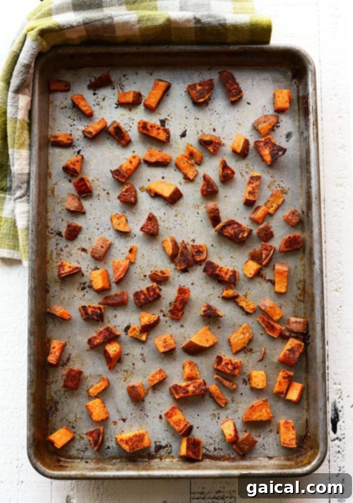 Crispy roasted sweet potato cubes on a baking sheet, ready to serve.