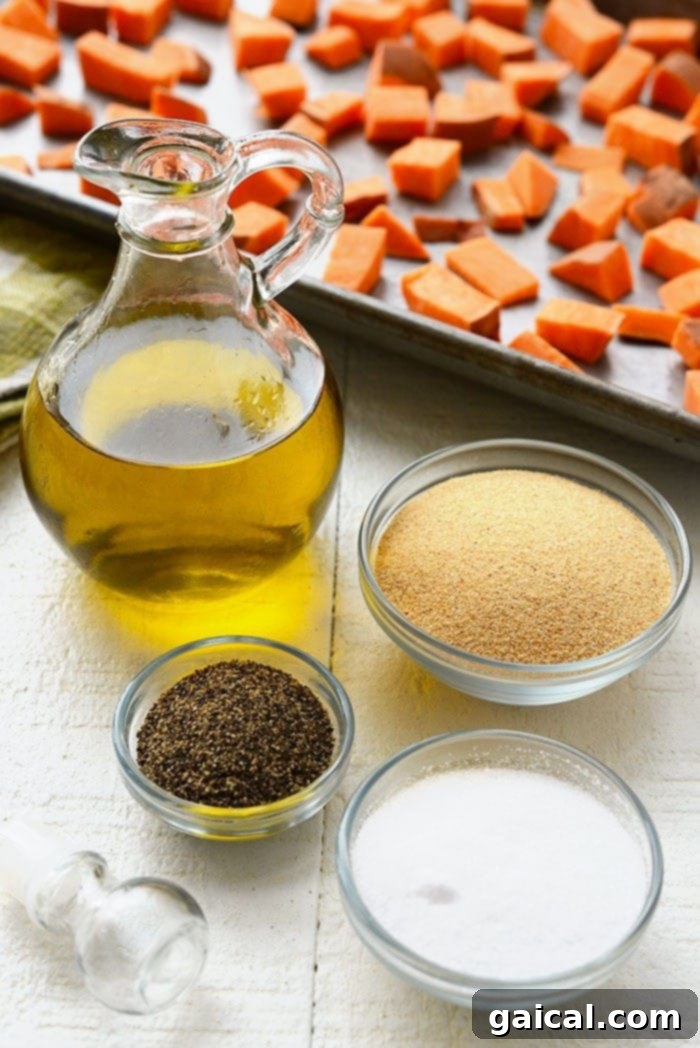 Raw sweet potatoes, olive oil, garlic powder, salt, and pepper arranged on a rustic surface.