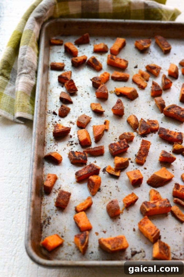 Crispy roasted sweet potatoes spread evenly on a baking sheet after cooking.