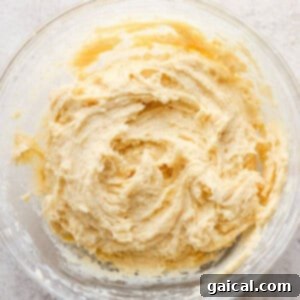 A bowl of freshly prepared cookie dough covered with plastic wrap, chilling in the refrigerator.