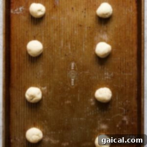 Raw cookie dough balls, scooped and shaped, arranged neatly on a baking sheet lined with parchment paper, spaced for even baking.