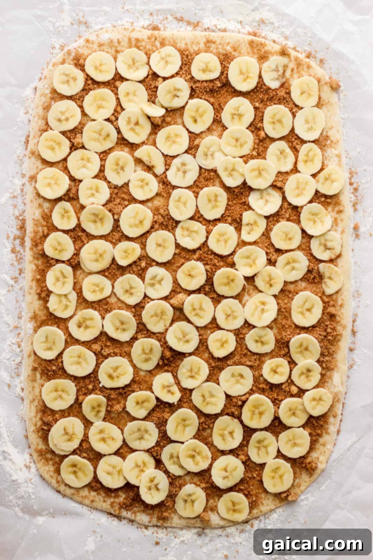 Nutty Brown Butter Banana Bread Cinnamon Rolls 4 Neatly sliced bananas arranged on a piece of parchment paper, ready for the cinnamon roll filling.