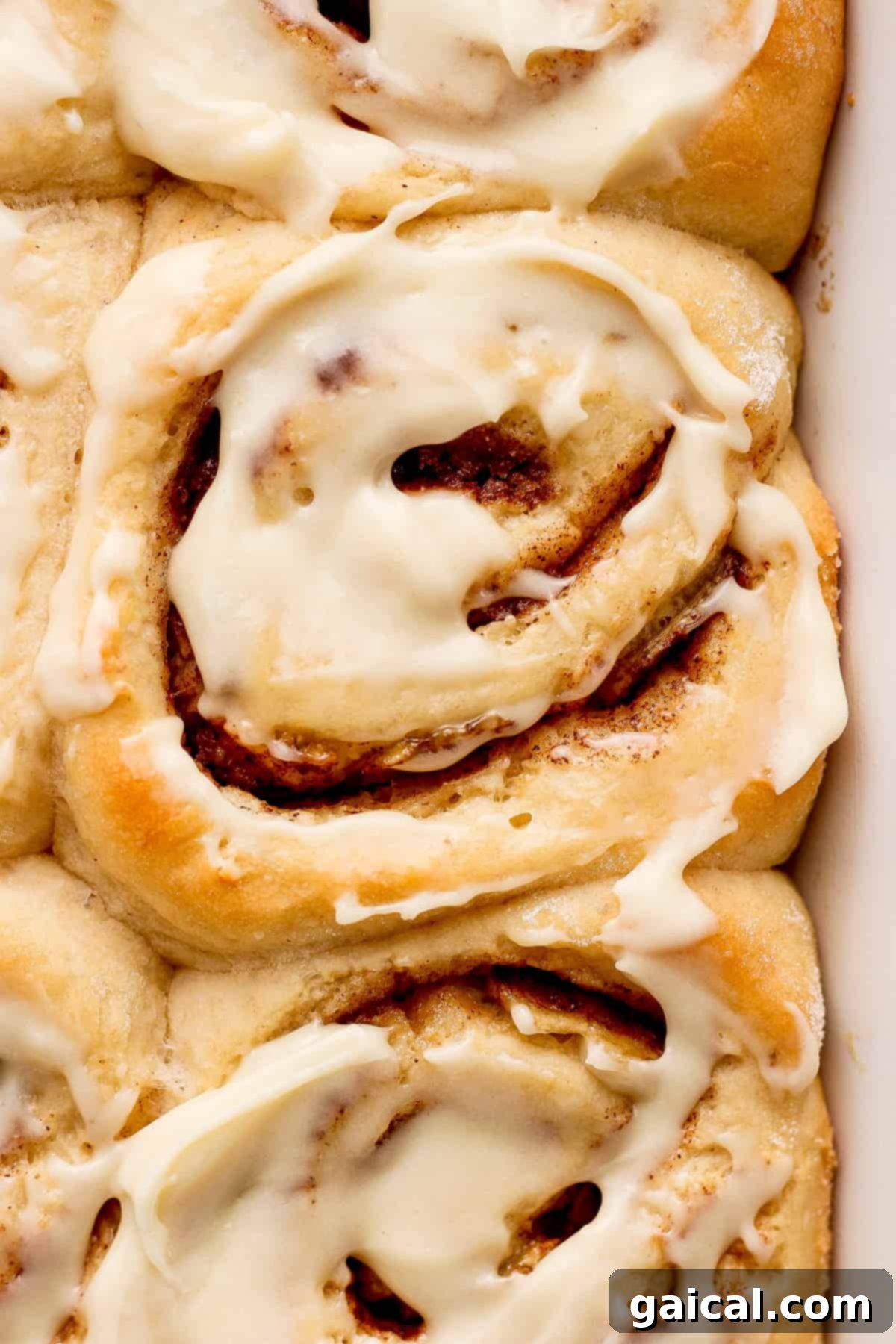 Nutty Brown Butter Banana Bread Cinnamon Rolls 6 A close-up of a baking dish filled with perfectly baked and iced cinnamon rolls, highlighting their golden-brown tops and creamy frosting.