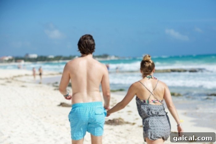 A couple enjoying a romantic long walk on the beach at Iberostar Grand Hotel Paraíso, with crystal clear waters.