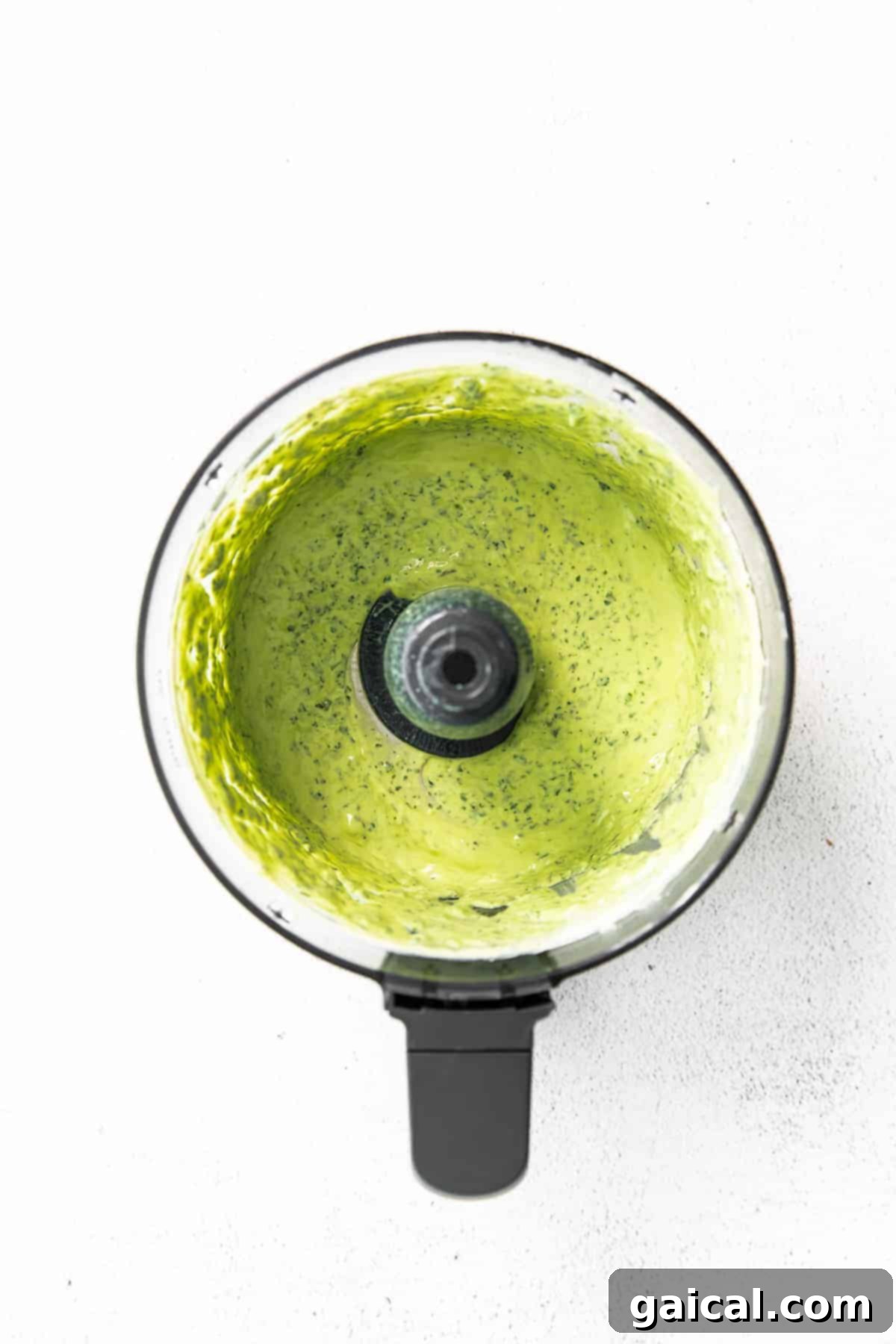 Blending Green Goddess Dressing in a Food Processor Green Goddess dressing being blended smoothly in a high-speed food processor.