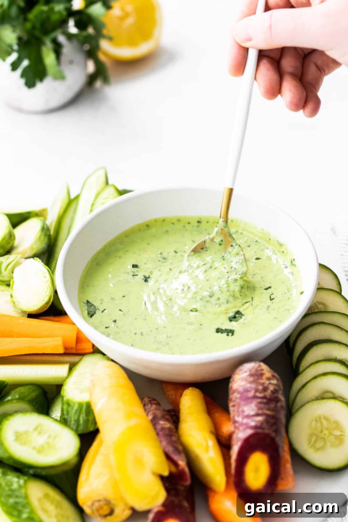 Creamy Green Goddess Dressing Ready to Serve A spoon scooping creamy Green Goddess dressing from a bowl, highlighting its perfect texture.