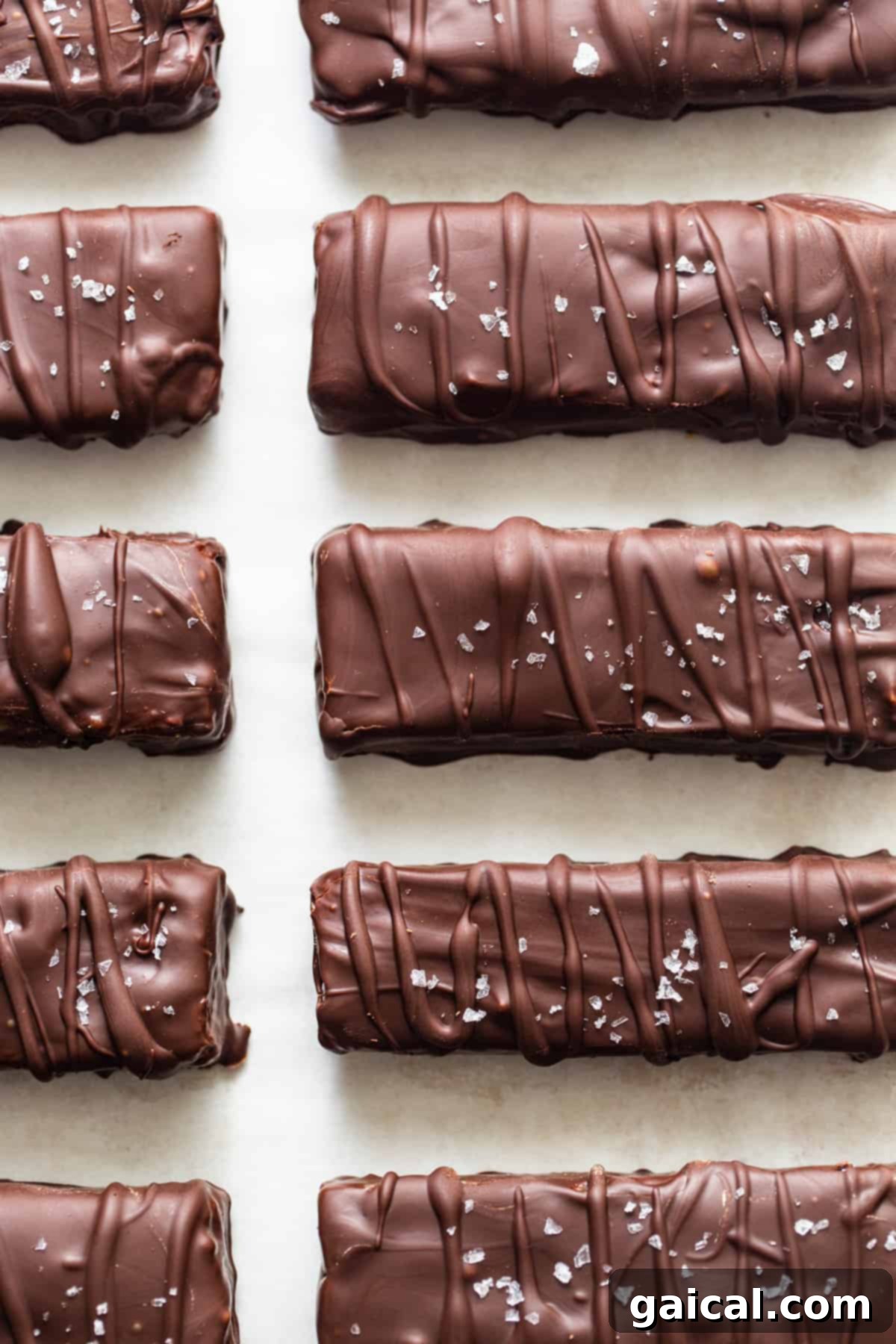 A row of freshly chocolate-covered protein bars carefully arranged on a white wire rack to set and harden.