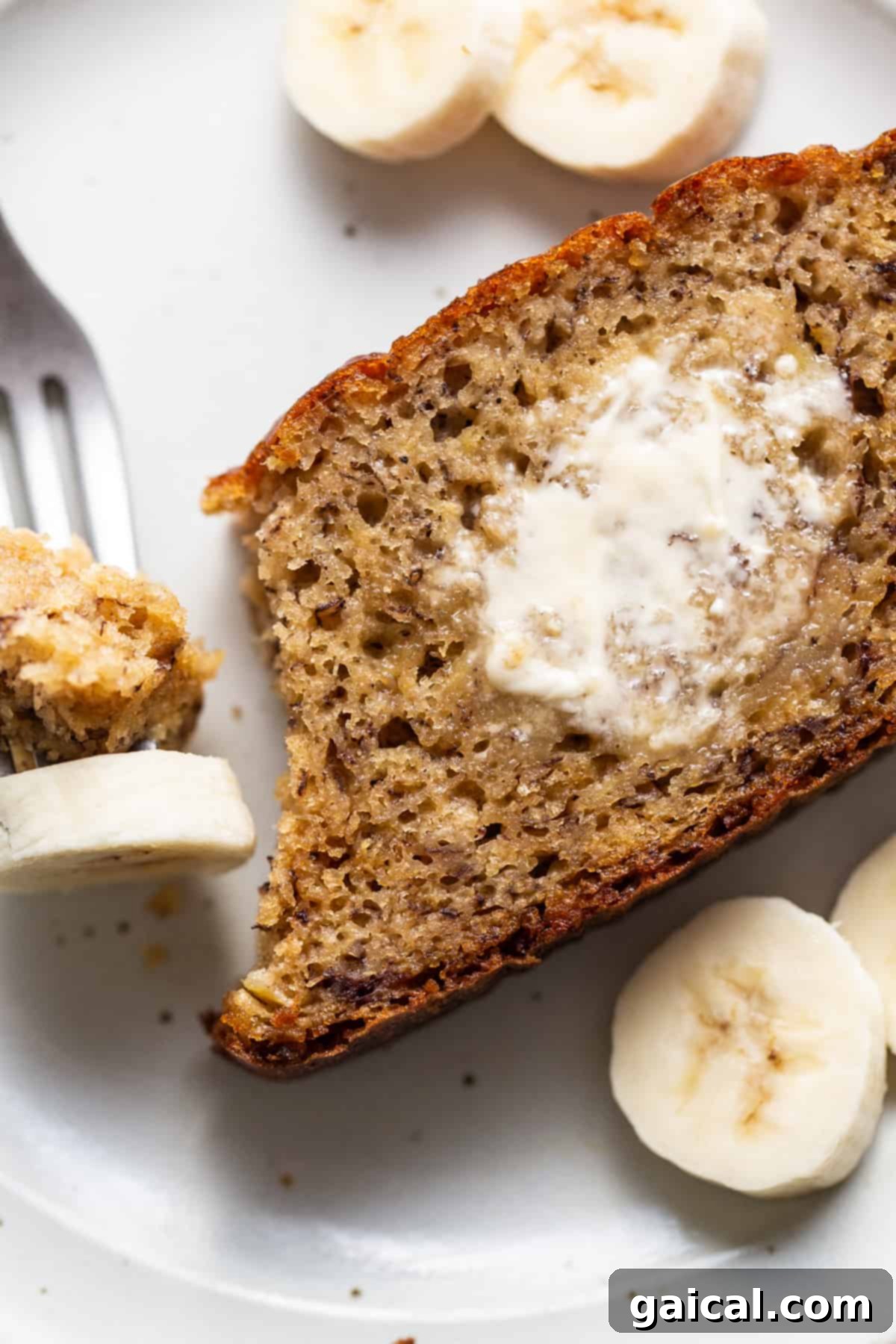 Protein-Boosted Banana Bread 2 A slice of protein banana bread on a plate with a fork, showing its moist texture.