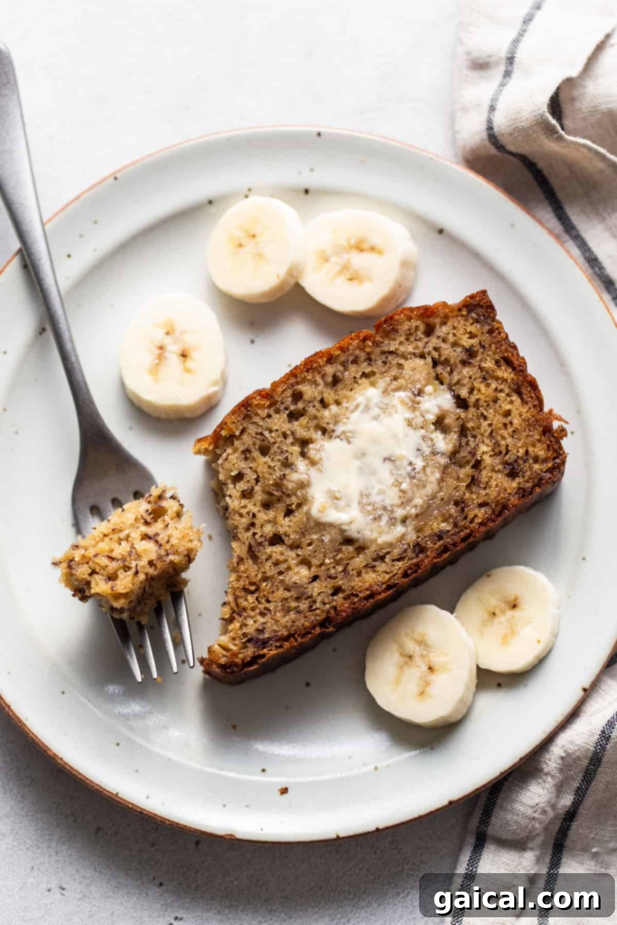Protein-Boosted Banana Bread 16 A perfectly baked slice of protein banana bread on a white plate with a fork.